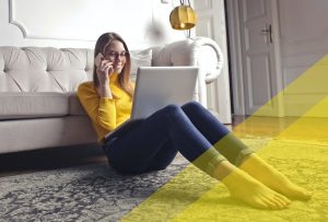 Chica joven en su casa contratando desde el teléfono y ordenador